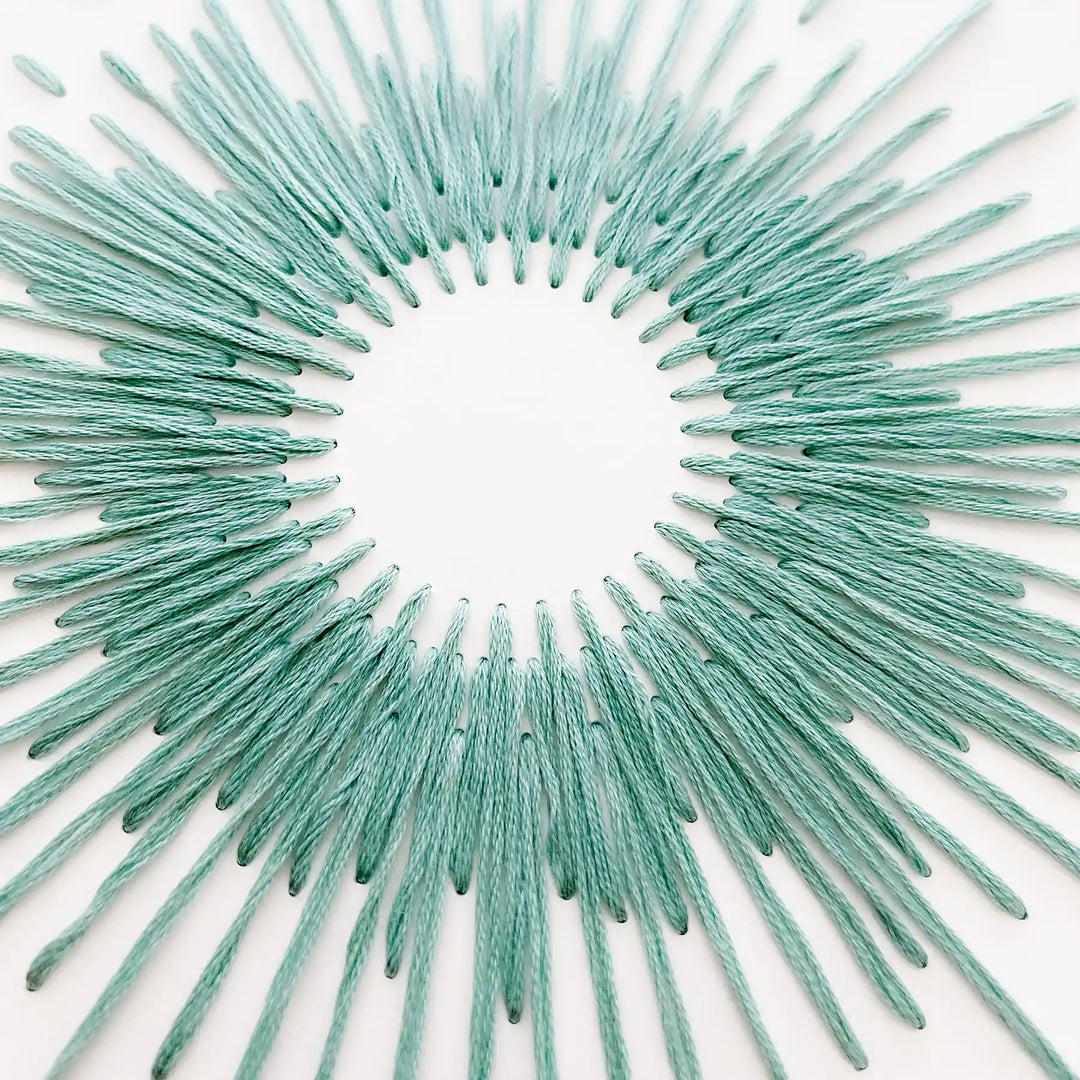 Teal decorative sunburst wall art on a white background