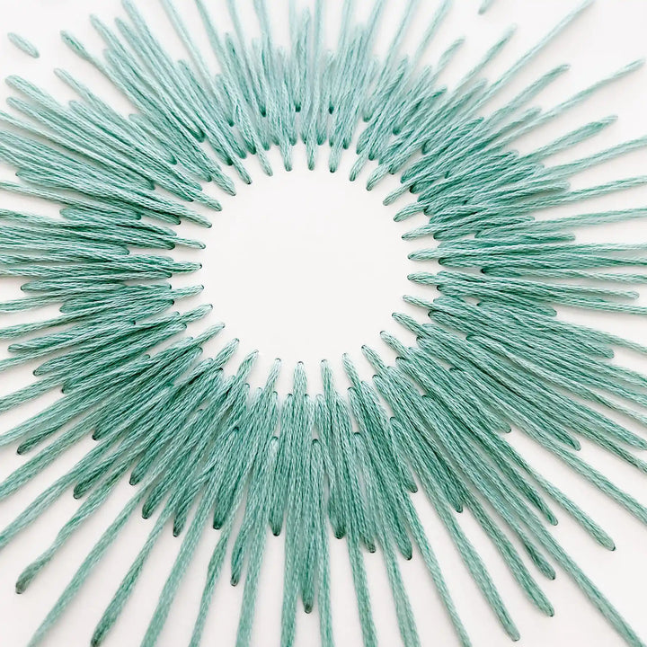 Teal decorative sunburst wall art on a white background