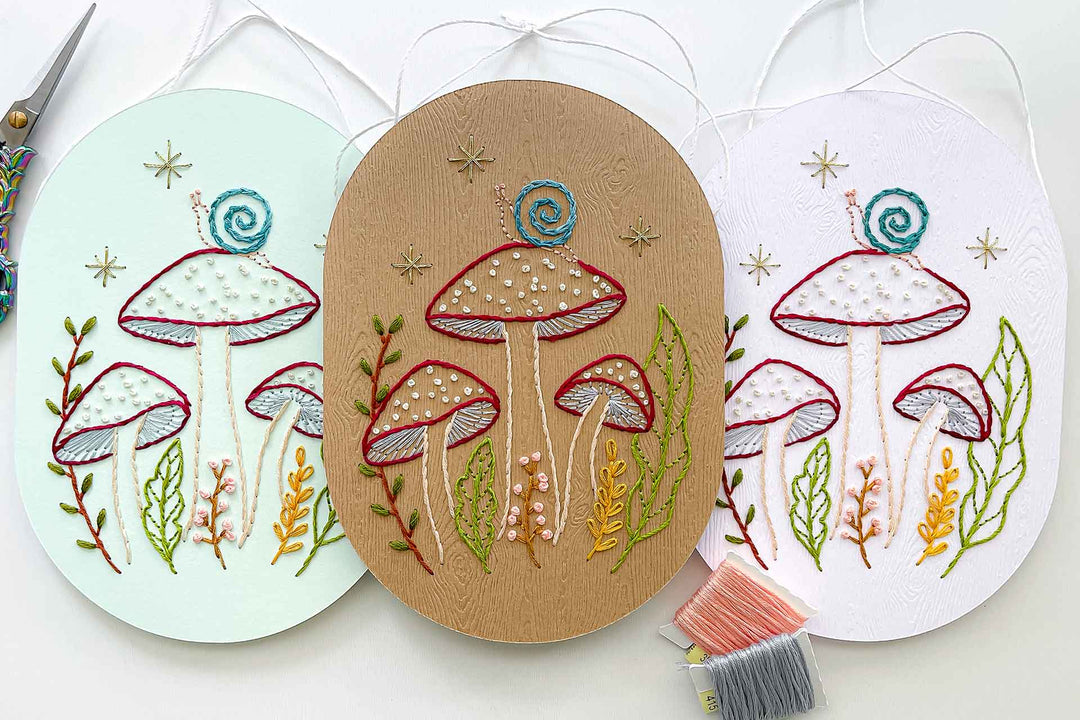 A flat lay of three finished paper embroidery art pieces.