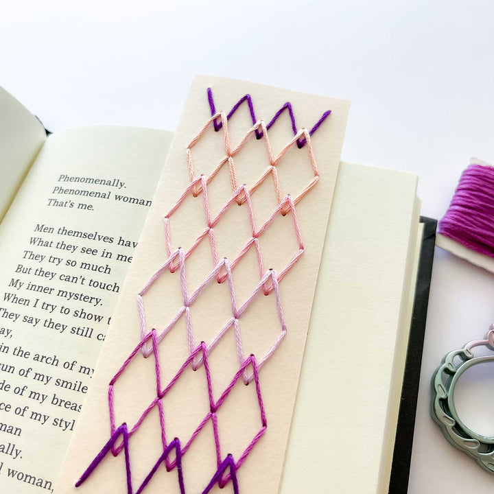 Decorative embroidered bookmark on a book with pink and purple thread