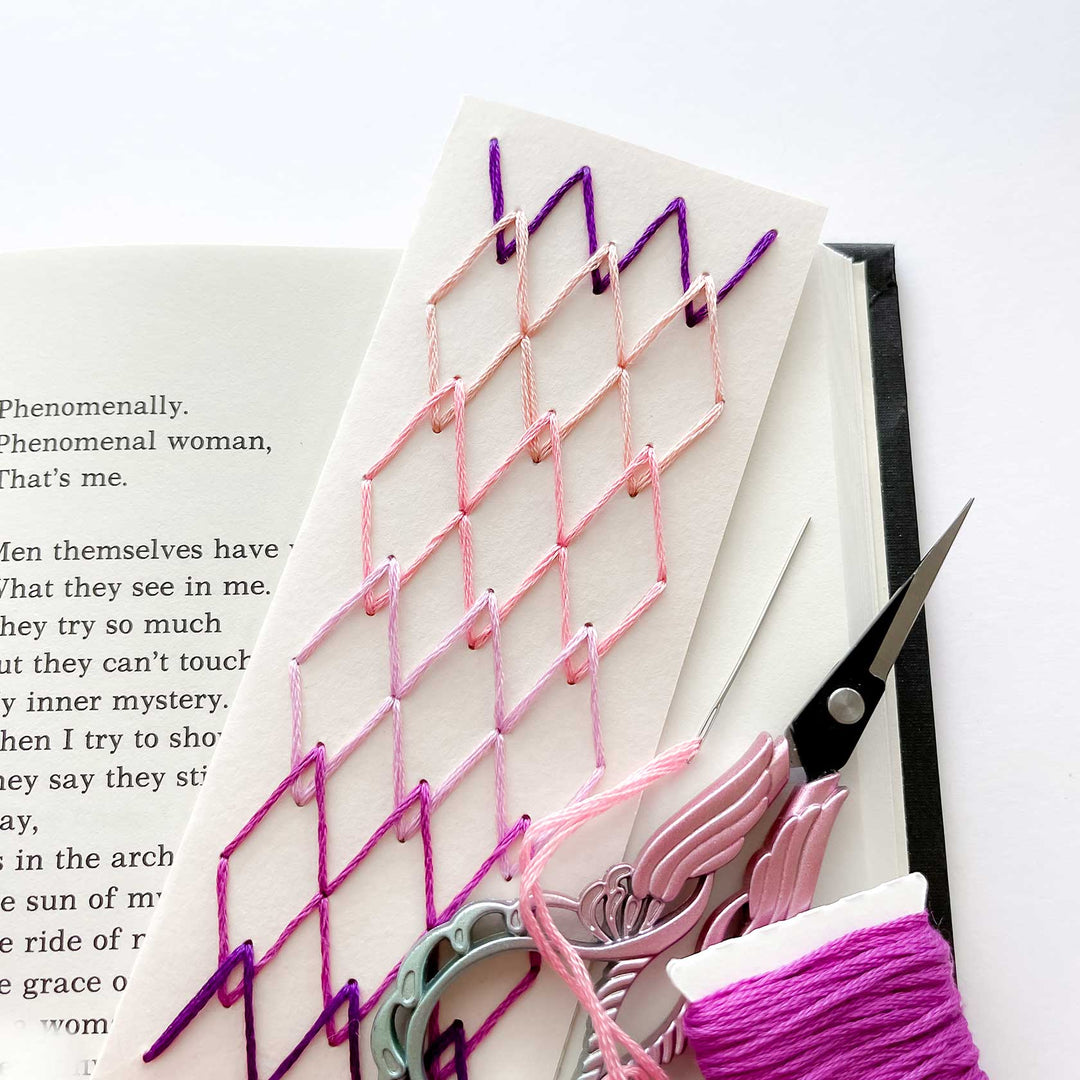 Embroidery bookmark with pink and purple thread on a book page