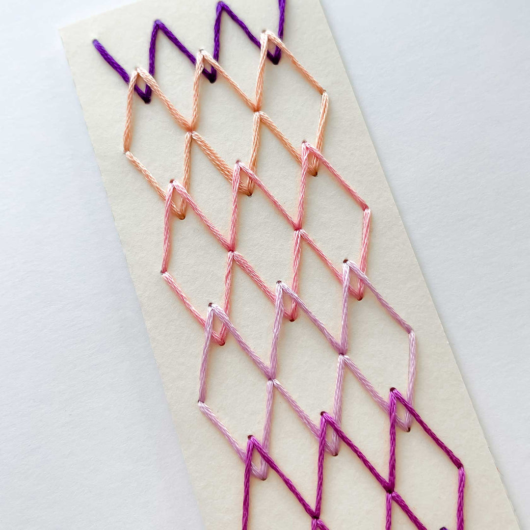 Embroidery with pink and purple thread on a white background