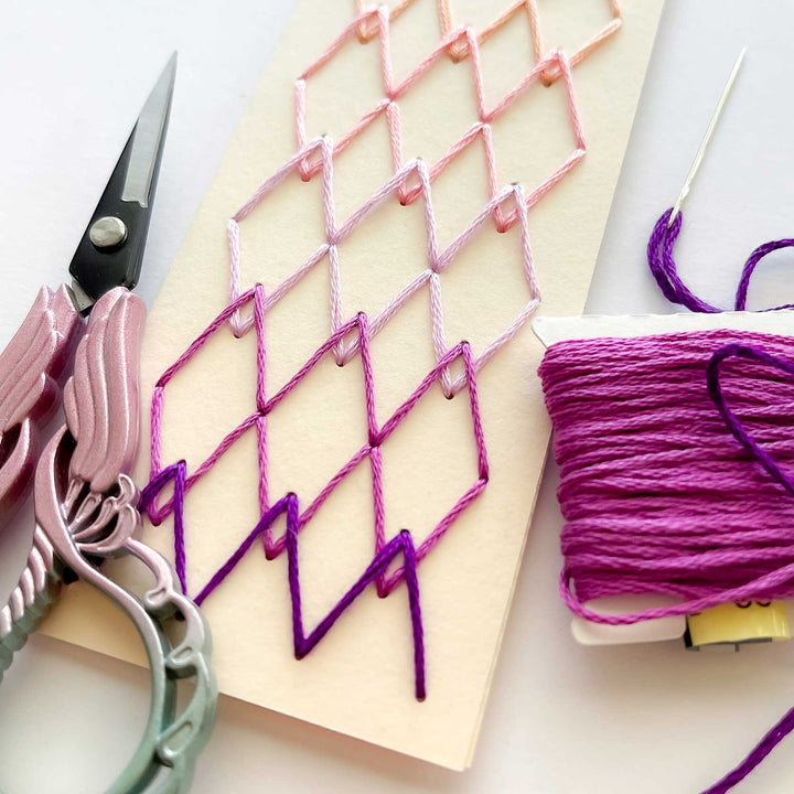 Crafting project with pink and purple thread on a white surface