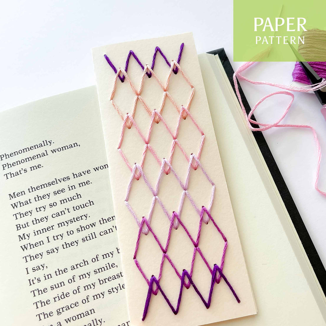 Embroidered paper pattern with pink and purple thread on a book