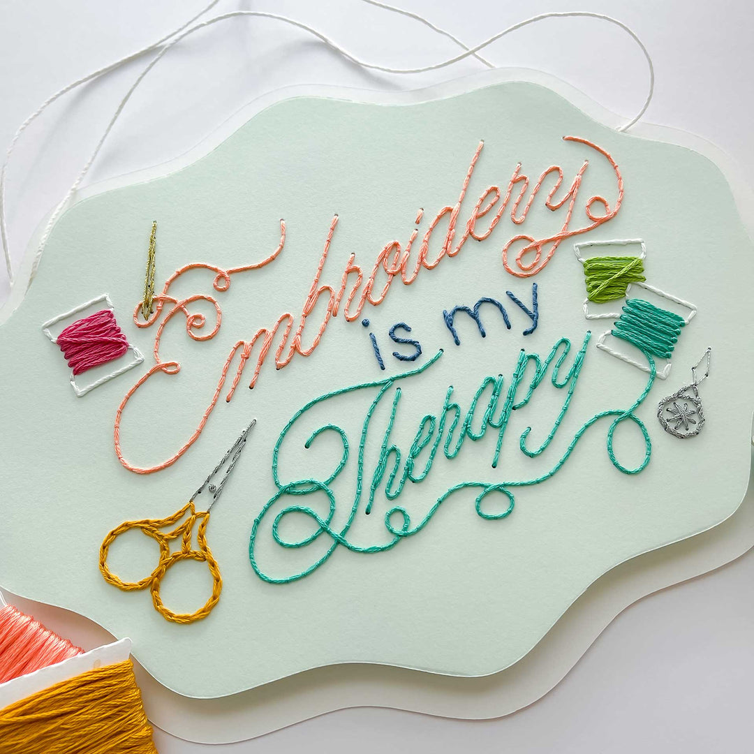 Embroidery paper with colorful thread and text 'Embroidery is my Therapy' on a light green background.
