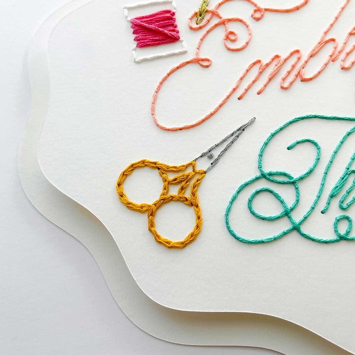 Embroidery paper with colorful thread and scissors on a white background