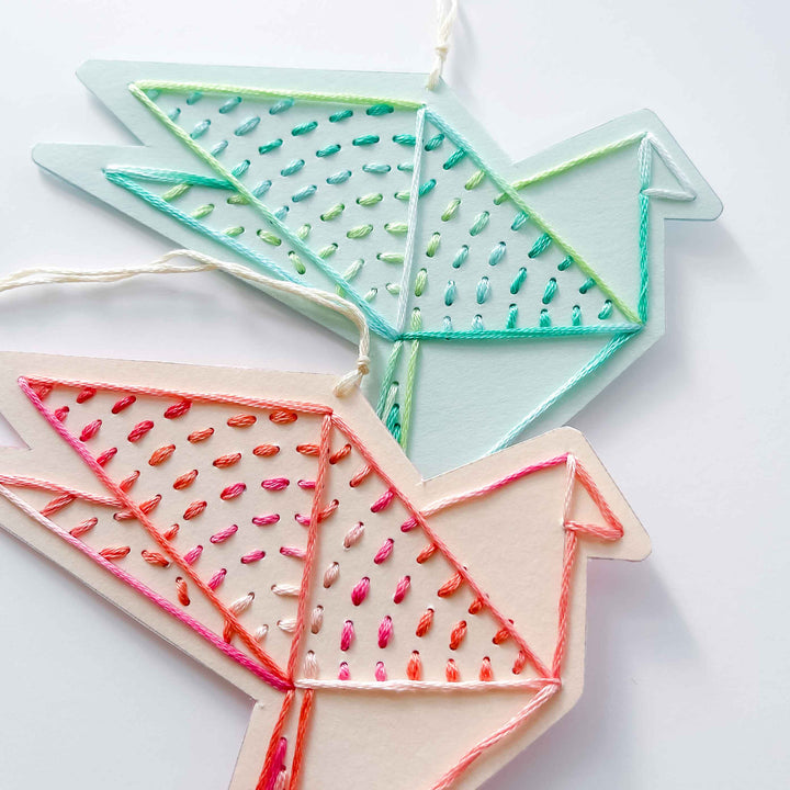 Two geometric-shaped decorative items with embroidered patterns on a white background