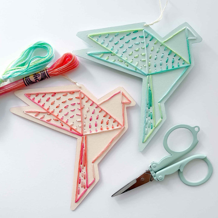 Decorative bird shapes with embroidery floss and scissors on a white background