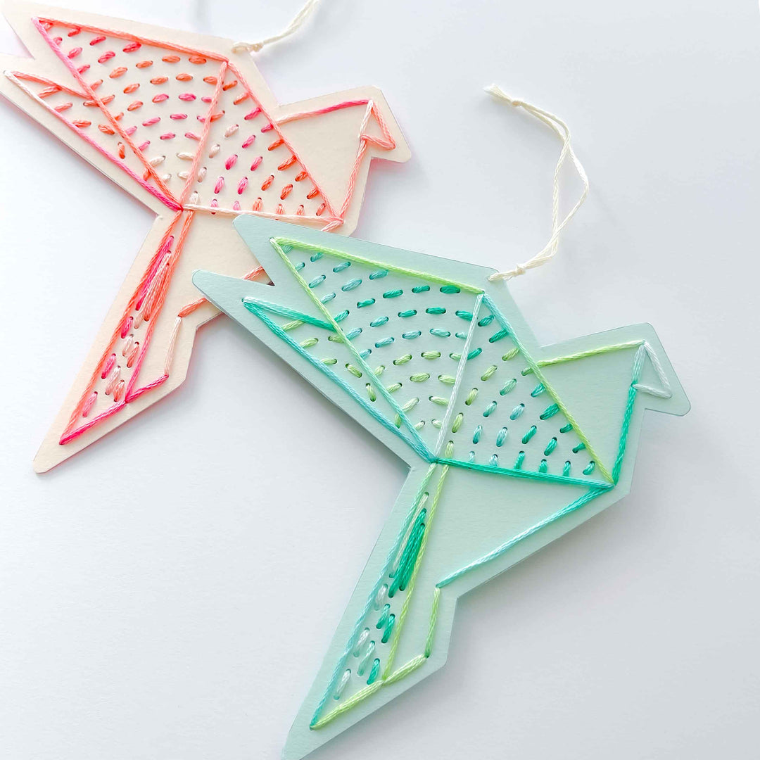 Two geometrically shaped ornaments with embroidered patterns on a white background